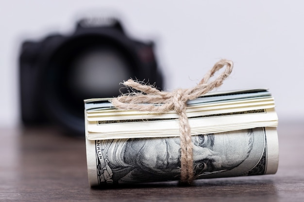 Geld in een rol vastgebonden met een touw in de buurt van de camera. Salaris voor het werk van een fotograaf