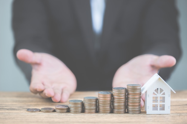 Foto geld van muntenstapelstijging groeiende groei met model wit huis op houten lijst.