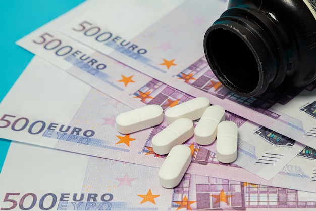 Geldpillen medicijnpillen op eurobiljetten op een blauwe achtergrond covid coronaviruspillen zijn in euro