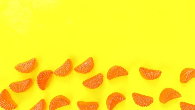 Gele achtergrond met vitamine C gummies in de vorm van stukjes sinaasappel. Ruimte voor tekst