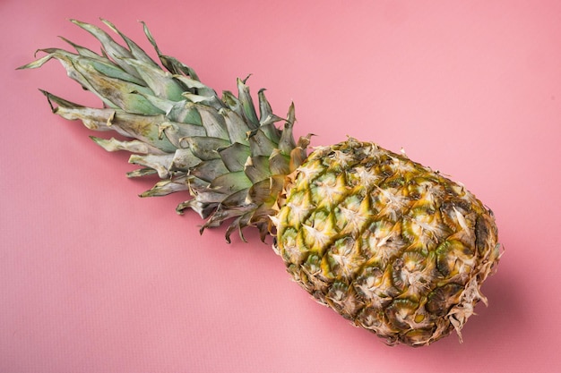 Gele ananas- of ananasset, op roze getextureerde zomerachtergrond, met kopieerruimte voor tekst