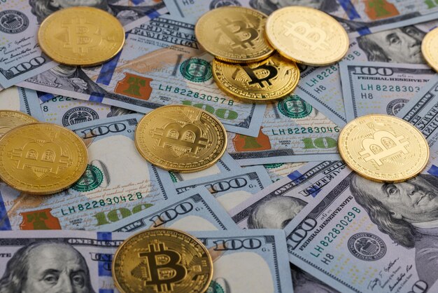 Gele bitcoin-munten verspreid over Amerikaanse dollar papieren bankbiljetten cryptocurrency en fiat geldwisselconcept