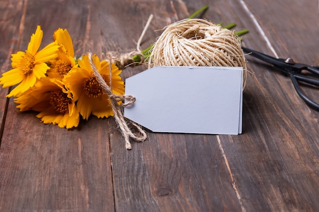 Gele bloemen en lege kaart op houten tafel close-up