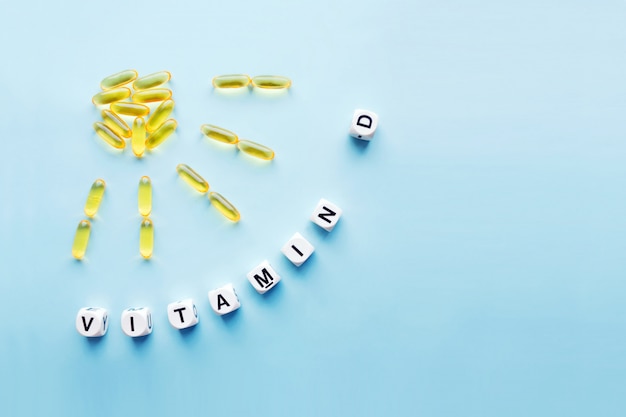 Gele capsules in de vorm van de zon met stralen en het woord vitamine d