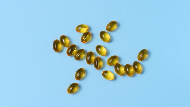 Gele capsules met visolie op een blauwe achtergrond bovenaanzicht