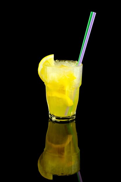 Gele cocktail met schijfje citroen, zomer verfrissende limonade met stro, over zwarte muur
