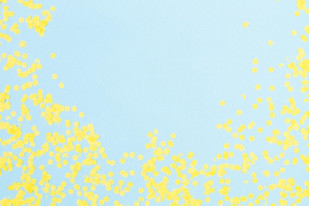 Gele confetti op een lichtblauwe achtergrond met kopieerruimte