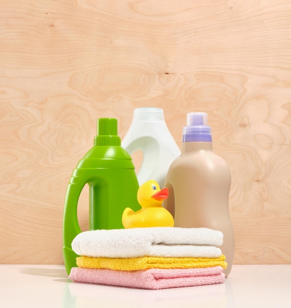 Gele eend zittend op wit geel roze handdoeken Drie flessen wasmiddel op een houten achtergrond