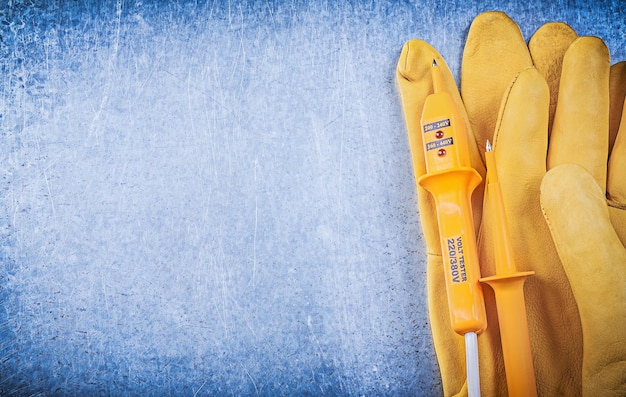 Gele elektrische tester beschermende handschoenen op metalen achtergrond kopie ruimte.