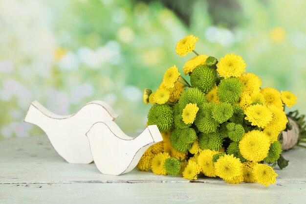 Gele en groene bloemen op houten tafel op lichte achtergrond