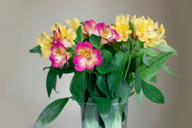 Gele en roze bloemen in een glazen vaas