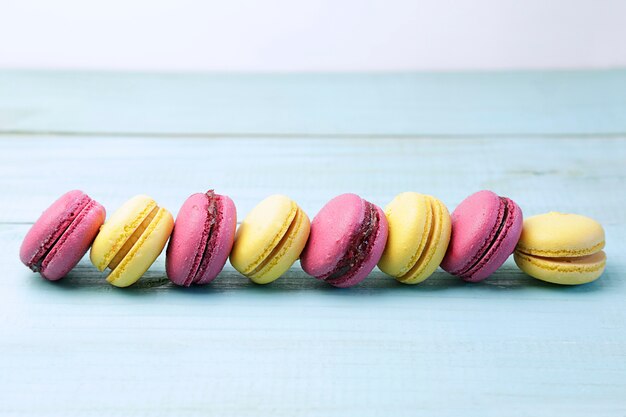 Gele en roze macarons over een turquoise oude houten tafel