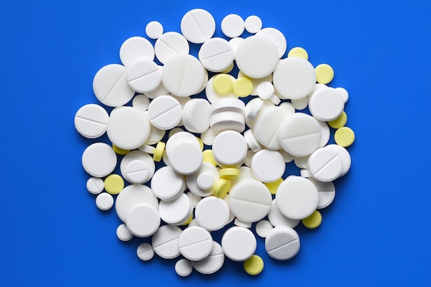Gele en witte tabletten verspreid op een blauwe medische tafel