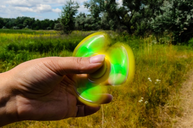 Gele fidget spinner draait in vrouwelijke hand