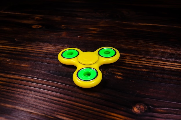 Gele fidget spinner op houten bureau