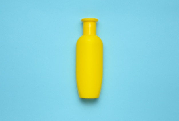 Foto gele fles shampoo op een blauwe achtergrond. trend van minimalisme. bovenaanzicht producten voor de douche. ruimte voor tekst.