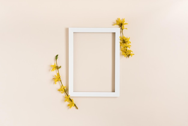 Gele forsythia bloemen rond een wit frame op een pastel beige achtergrond Plat lag en kopieer ruimte Het concept van een wenskaart voor moederdag vrouwendag verjaardag Pasen