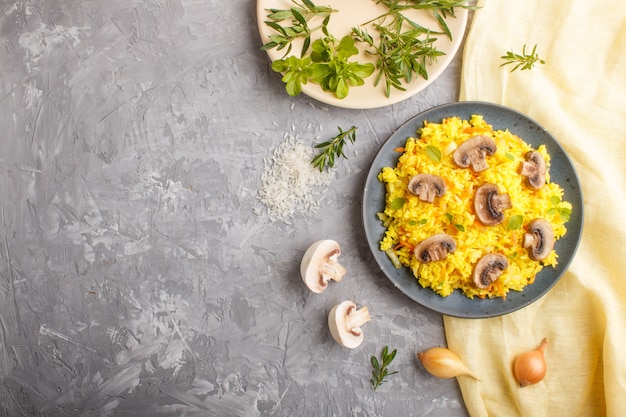 Gele gebakken rijst met champignons, champignons, kurkuma en oregano op blauwe keramische plaat. bovenaanzicht.