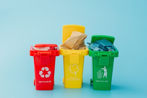 Gele, groene en rode prullenbakken met kringloopsymbool op blauw