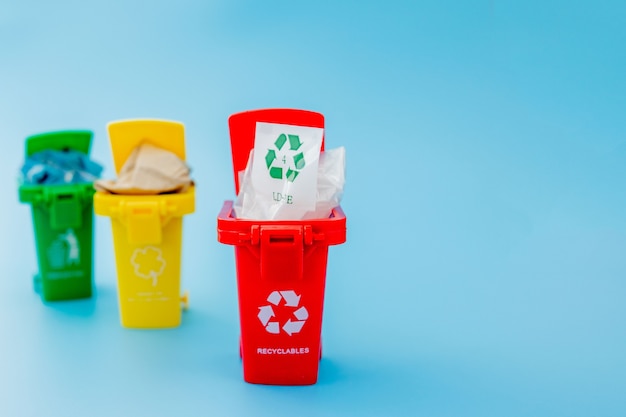 Gele, groene en rode prullenbakken met kringloopsymbool op blauwe achtergrond. houd de stad netjes, laat het recyclingsymbool achter. natuurbeschermingsconcept.