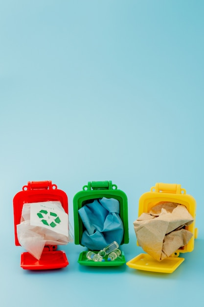 Gele, groene en rode prullenbakken met recycle symbool op blauwe achtergrond. Houd de stad netjes, laat het recyclingsymbool achter. Natuurbeschermingsconcept.