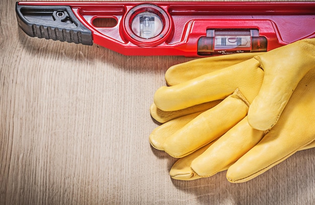 Gele handschoenen en rood bouwniveau op een houten bord