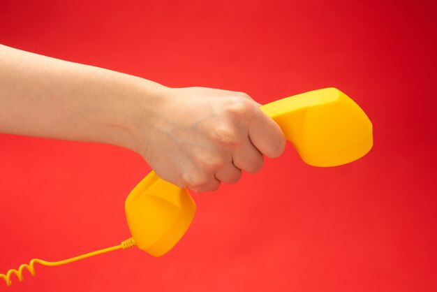 Gele handset in de hand van de vrouw.