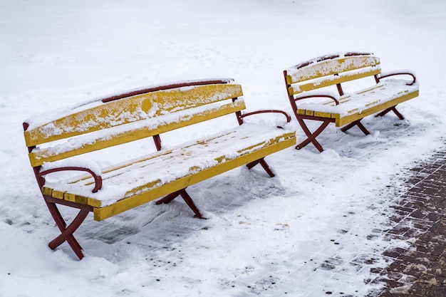 Gele houten parkbanken bedekt met sneeuw