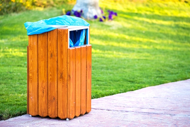 Gele houten vuilnisbak buiten aan de kant van de stoep in het park