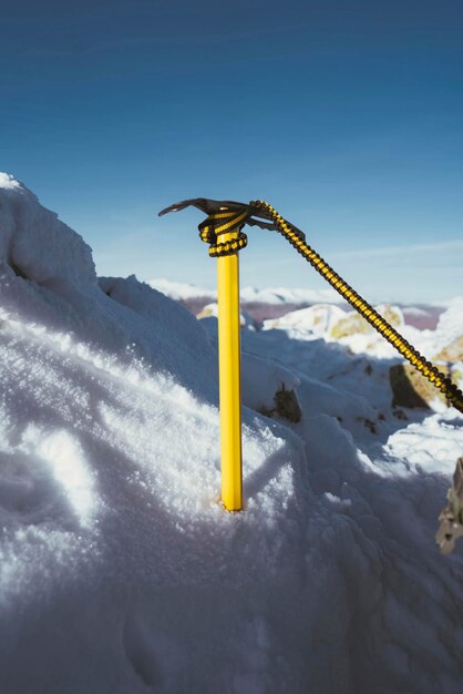 Foto gele ijsbijl in de sneeuw