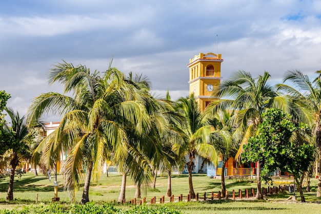 Gele klokkentoren met palmen aan de voorkant dicht bij Ancon strand Trinidad Cuba