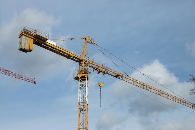 Foto gele kraan werkt in de buurt van betonnen huiskarkas