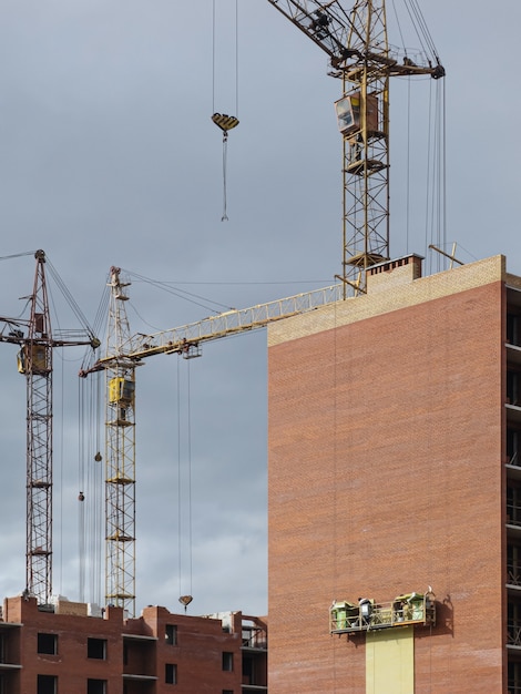 Gele kranen op de achtergrond van gebouwen in aanbouw