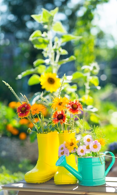 Gele laarzen en groene gieter met bloemen