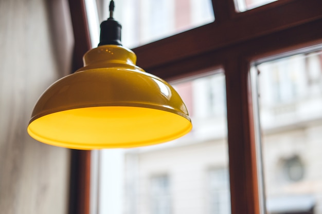 Gele lamp over houten tafel.