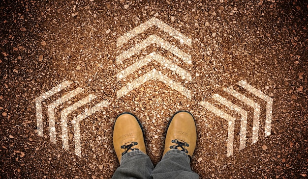 Gele leren schoenen en drie krijtachtige pijlen op grondbeslissingsconcept