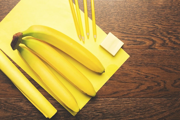 Gele leveringen en bananen op houten bureau