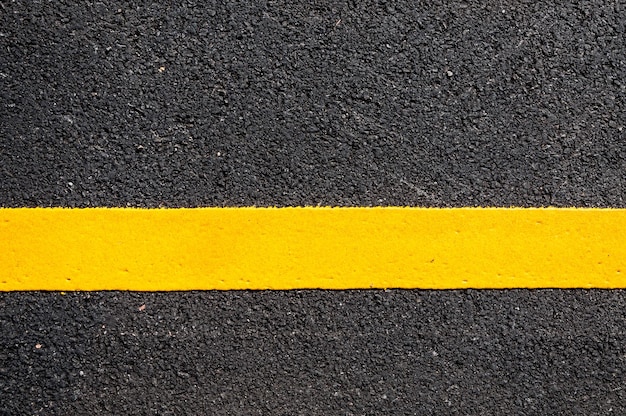 Gele lijn op nieuw asfaltdetailStraat met gele lijntextuur