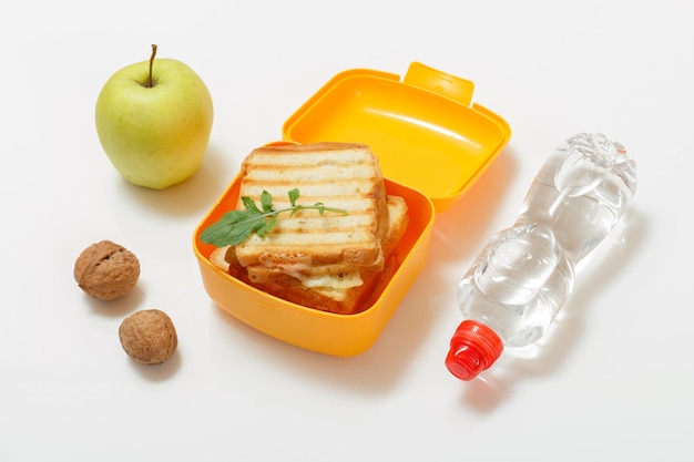 Gele lunchbox met geroosterde sneetjes brood, kaas en groene peterselie