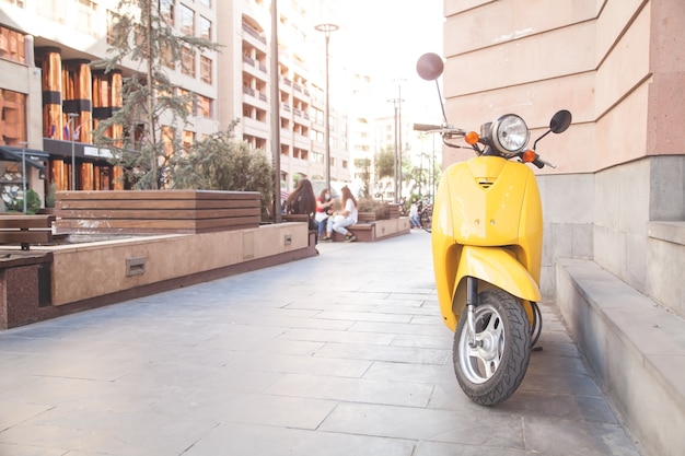 Gele moderne bromfiets in een stad.