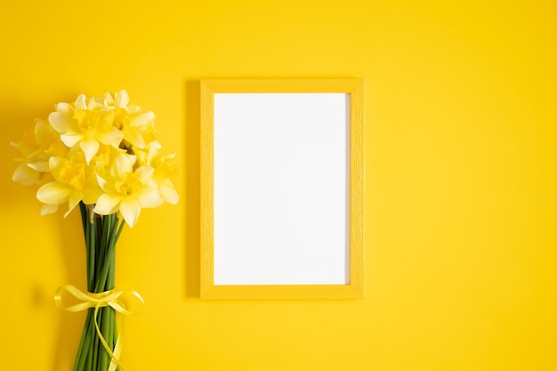 Gele narcissen bloemen en fotolijstjes op geel plat lag bovenaanzicht