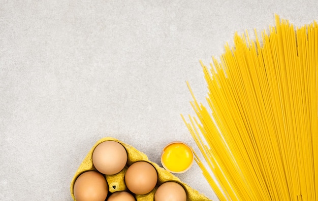 Gele noedels spaghetti met eieren in lade en gebroken ei plat lag kopieerruimte