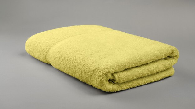 Gele opgevouwen badhanddoek op ultiem grijs