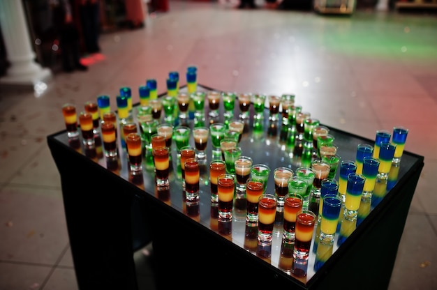 Gele, oranje en groene shots op spiegeltafel.