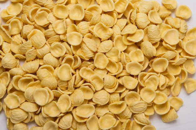 Gele orecchiette pasta op houten tafel