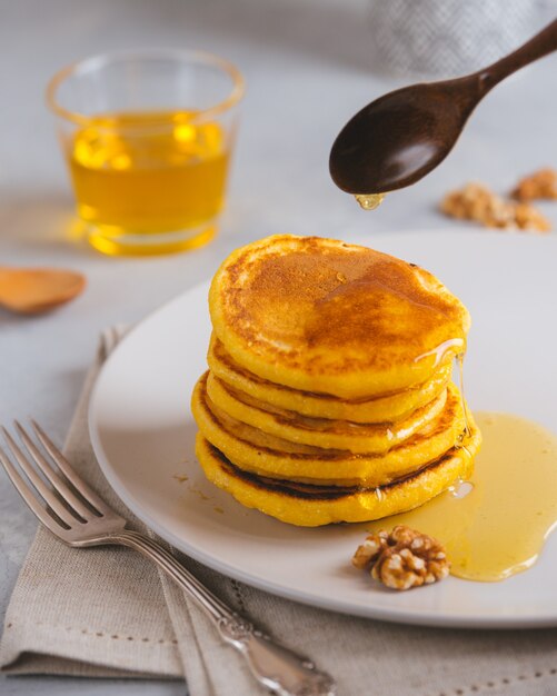 Gele pannenkoeken met maïsmeel en kurkuma, opgemaakte honing en rode druiven