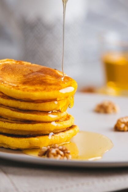 Gele pannenkoeken met maïsmeel en kurkuma, opgemaakte honing en rode druiven