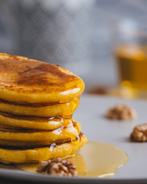 Gele pannenkoeken met maïsmeel en kurkuma, opgemaakte honing en rode druiven