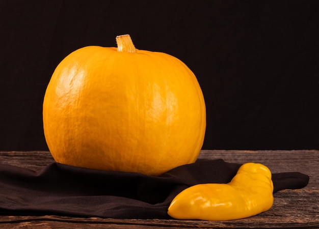 Gele pompoen en lange peper op een houten oude tafelruimte voor tekst