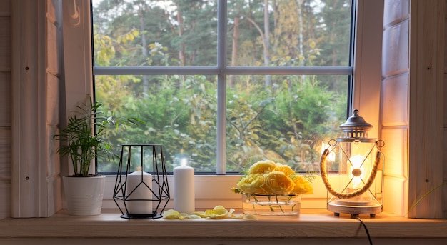 Gele rozen op vensterbank, kaarsen, herfstbladeren, lantaarn.